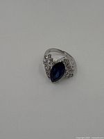 Top view showing marquise-cut blue sapphire with diamond accent stones and band swirl design