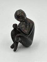 Front and side angle of seated bronze netsuke woman figurine showing detailed facial features and posture.