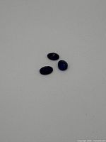 Three oval-shaped oval opal gemstones on a grey surface, showing their size and shape.