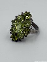 Close-up of ring top showing cluster of oval and round peridot gemstones set in sterling silver prong setting.