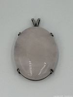 Front view of oval rose quartz pendant showing smooth polished stone with silver prong setting and silver bail.