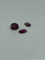 Three loose ruby gemstones on a neutral background showing various sizes and cuts.