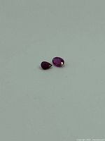 Two loose ruby gemstones on grey background, showing shape and size