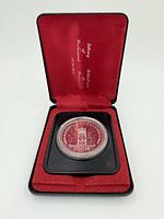 Coin with castle design in display case with red velvet lining