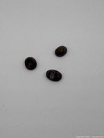 Three small dark-colored oval-shaped faceted opal gemstones visible from top view.