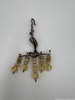 Front view of a tarnished silver pendant with five hanging bead strands on a white background.