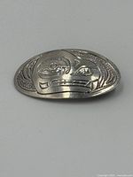 Front view of sterling silver bear pendant showing engraved stylized bear design