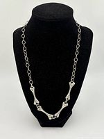 Full view of sterling silver bones necklace on black mannequin bust showing bone-shaped links and chain