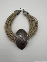 Top view of the sterling silver bracelet showing the textured silver centerpiece and multiple natural fiber strands making up the wristband.