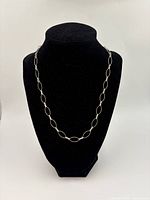 Sterling silver chain necklace displayed on black stand showing overall shape and design
