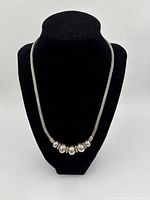 Necklace displayed on black bust showing front design and beads