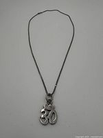 Full view of the sterling silver necklace with Om symbol pendant laid flat to show length and design.