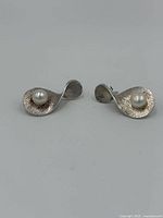 Front view of the pair of sterling silver earrings with white pearls, showing curved textured design and pearl placement.
