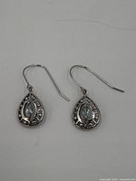 Close-up image of a pair of sterling silver teardrop-shaped earrings with pear-shaped light blue topaz stones in the center and surrounding silver design detail.