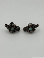 Pair of vintage turquoise and sterling silver earrings viewed from front showing design and turquoise stones.