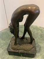 Rear angled view of bronze female nude statue on granite base