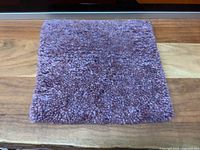 Full view of the square wool mat showing color and shape