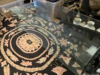 Full view of bent glass coffee table on floral rug showing glass shelf in place