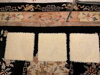 Front view three ivory wool mats on patterned rug