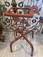 Full view of metal pedestal showing geometric frame and three legs