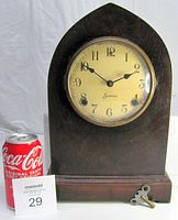 Front view of antique Sessions beehive wooden mantel clock next to a Coca-Cola can for scale.