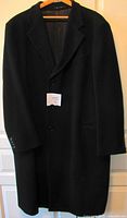 Front view of black Armani men's full length coat on hanger showing buttoned closure and lapels.