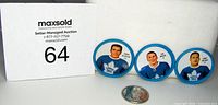 Three Toronto Maple Leafs metal hockey coins placed next to a quarter for scale, showing the full lot including player portraits and blue border