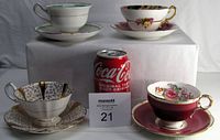 All four teacups displayed with matching saucers alongside a Coca-Cola can for size reference.