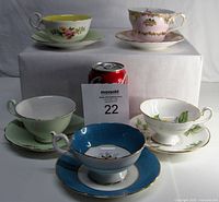 Lot of five bone china teacups with matching saucers displayed with a soda can for scale.