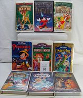 Photo showing all 9 Walt Disney VHS tapes including Bambi, Fantasia, Winnie The Pooh, Pinocchio, Robin Hood, Peter Pan, Sleeping Beauty, Cinderella, and Lady and the Tramp, neatly arranged with original clam shell cases.