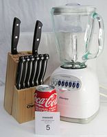Osterizer blender with glass pitcher and control panel showing 12 speed options and Master Chef wooden knife block with six steak knives and two additional kitchen utensils, Coca Cola can for scale