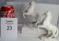 Both porcelain horse figurines side by side next to a Coca-Cola can for scale, showing white glossy finish and base.