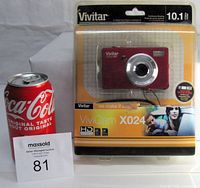 Vivitar ViviCam X024 digital camera in original retail sealed packaging with red camera visible, next to a Coca-Cola can for scale.