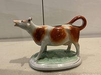 Left side profile of porcelain cow creamer on base