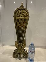 Front view of closed brass fireplace screen beside water bottle for scale