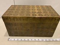 Front view of brass-tone metal box with ruler for scale