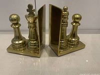 Front view of both brass chess bookends showing pieces and L-shape supports