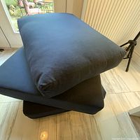Stacked dark blue Sunbrella cushions showing thickness and shape