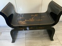 Full view of bench front showing curved arms, black lacquer finish and gold painted scene on seat