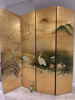 Full view of four-panel gold lacquer screen with cranes and landscape
