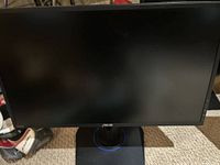 Front view of the Asus monitor showing screen, stand with blue-lit ring, no visible damage.