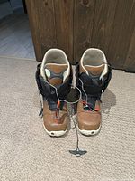 Front view of the pair of Burton Ambush snowboard boots in brown/black color showing speed lacing system.