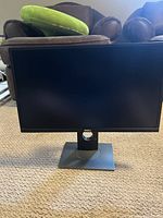 Front view of Dell 24-inch monitor, showing screen and stand on carpeted floor.