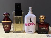 Four different women's perfume bottles displayed side by side against a dark background.