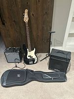 Overview of bass guitar, two amps, gig bag, speaker stand and cable