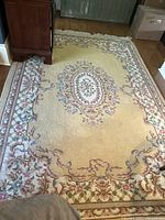 Overhead view of entire rug showing floral pattern, beige field and border