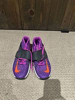 Front view of Nike Zoom Train Command training shoes showing purple mesh upper with black strap and orange swoosh logos.