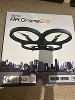 Box of Parrot AR Drone 2.0 with branding and features such as HD camera and smartphone control shown on front.
