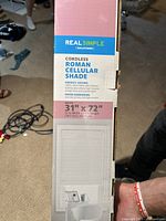 Front view of the box showing brand REAL SIMPLE Solutions, product name Cordless Roman Cellular Shade, dimensions 31" x 72", white color, energy saving and room darkening features.