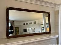 Front view of rectangular oak frame mirror with brass corner accents